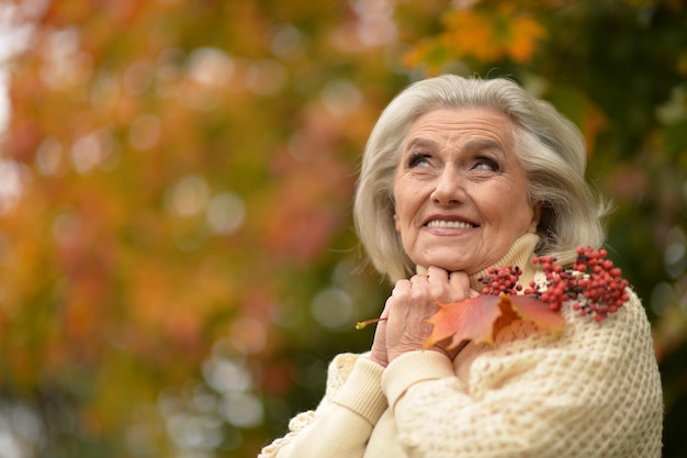 Senior hermosa mujer sosteniendo hojas de otoño y bayas