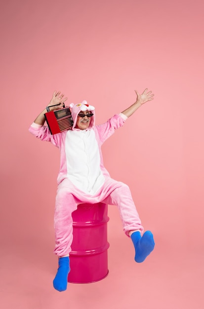 Senior Hipster Mann in stilvoller rosa Kleidung auf rosa Hintergrund isoliert. Technisch und fröhlich