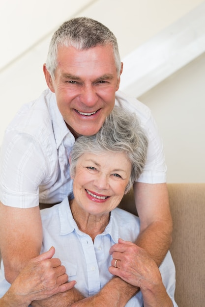 Senior hombre abrazando a esposa en el sofá