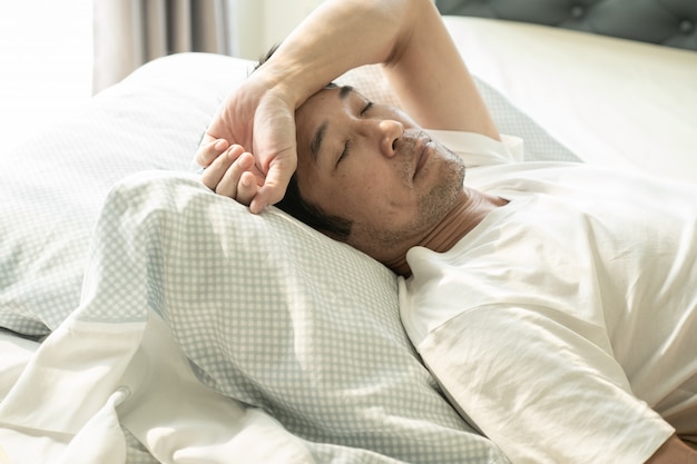 Senior hombre de asiam durmiendo en la cama