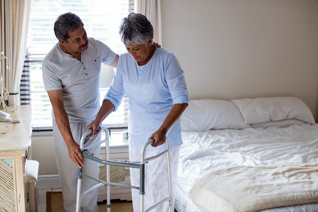 Senior hombre ayudando a senior mujer a caminar con andador