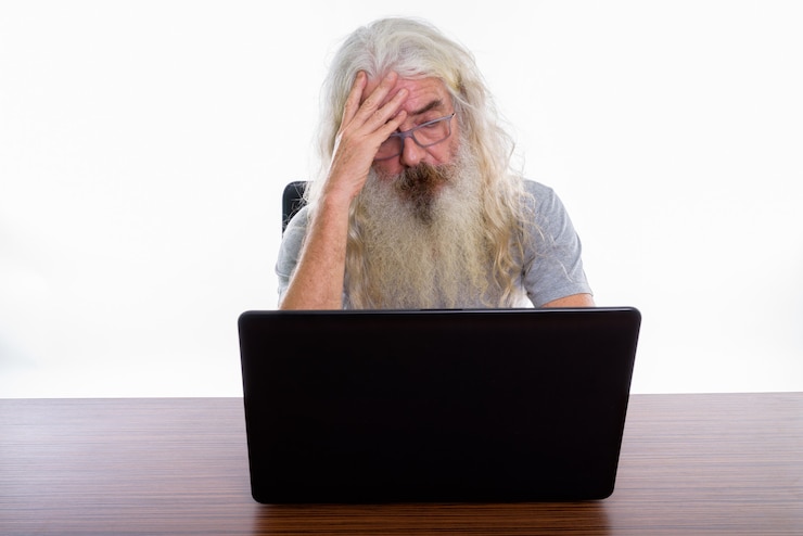 Foto senior hombre barbudo con anteojos mientras usa el portátil