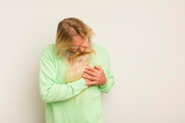 Foto senior hombre barbudo fresco que parece triste herido y con el corazón roto sosteniendo ambas manos cerca del corazón llorando y sintiéndose deprimido