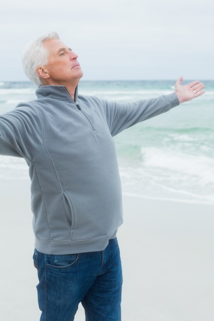 Senior hombre con los brazos extendidos en la playa