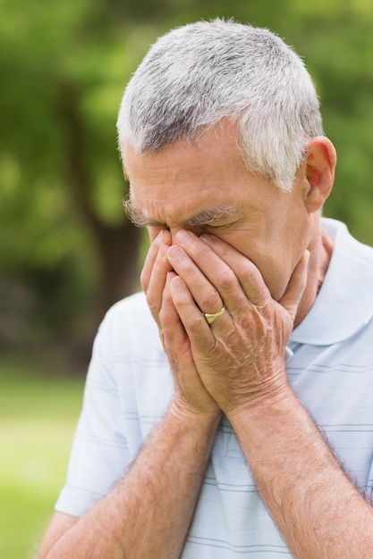 Senior hombre con la cabeza en las manos en el parque