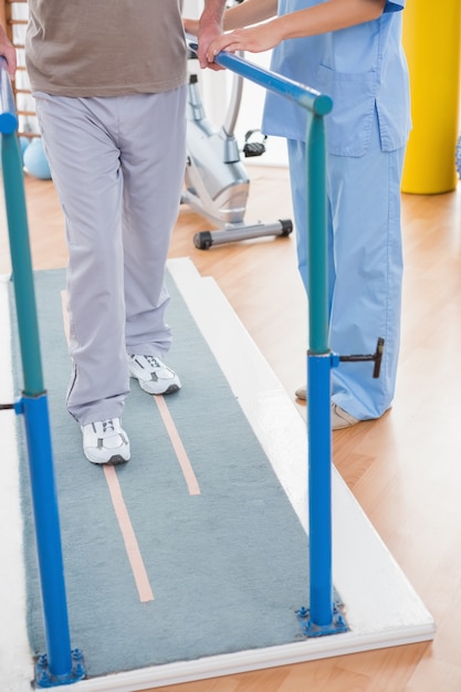 Senior hombre caminando con ayuda del terapeuta