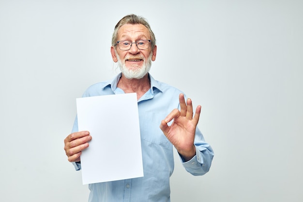 Senior hombre canoso hoja en blanco de papel gesto manos sonrisa fondo claro