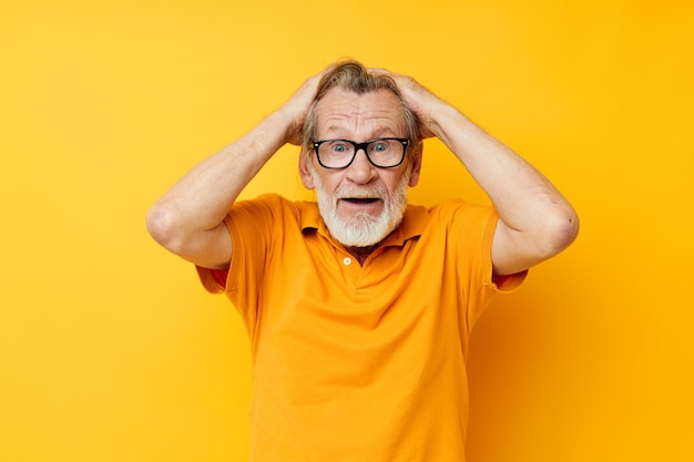 Senior hombre canoso posando camiseta amarilla gafas fondo amarillo