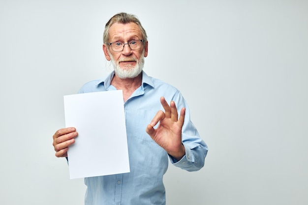 Senior hombre canoso sosteniendo una hoja de papel copyspace posando antecedentes aislados