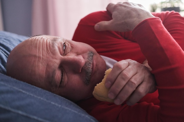 Senior hombre caucásico comiendo pastel escondiéndose de todos