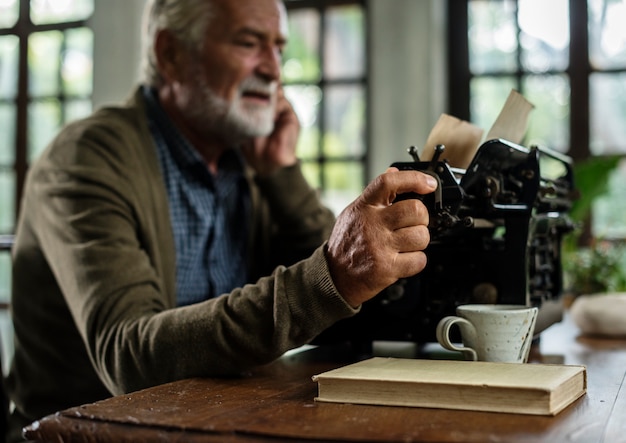 Senior hombre caucásico con máquina de escribir vintage