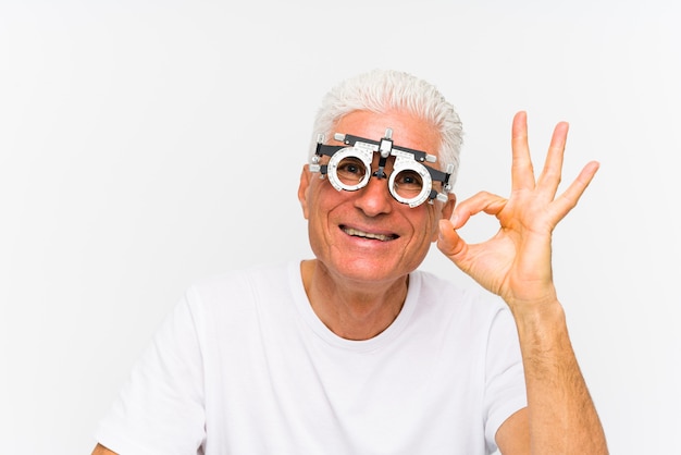 Senior hombre caucásico vistiendo un marco de prueba optometrista alegre y confiado mostrando gesto bien.