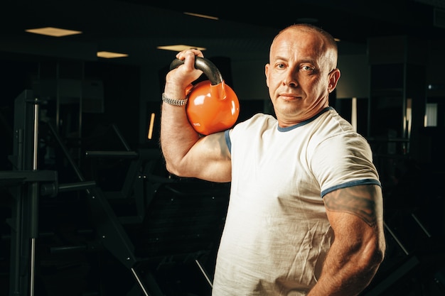 Senior hombre de unos cincuenta años levantando pesas en un gimnasio