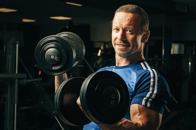 Senior hombre de unos cincuenta años levantando pesas en un gimnasio