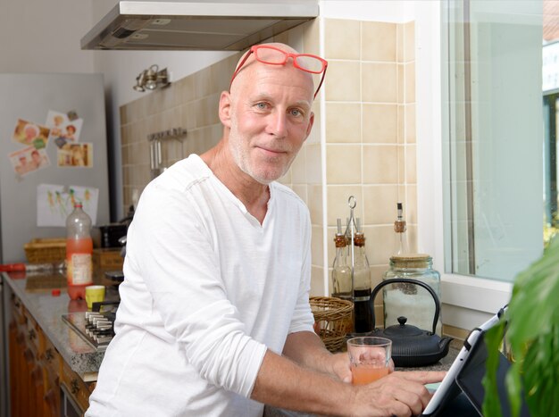 Senior hombre en cocina usando tableta