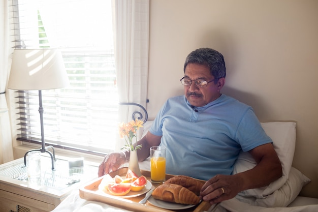 Senior hombre desayunando en la cama