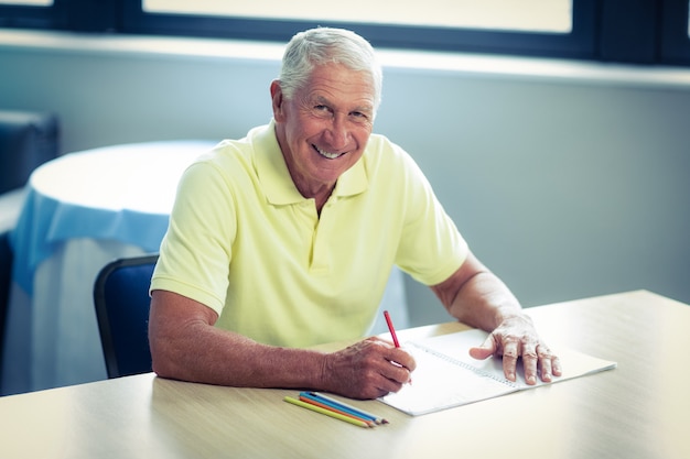 Senior hombre dibujando con un lápiz de color en el cuaderno de dibujo