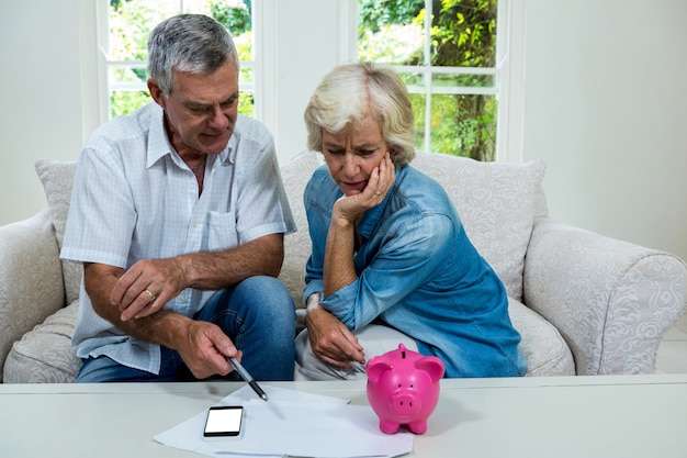 Foto senior hombre discutiendo con su esposa con respecto a los ahorros en el sofá