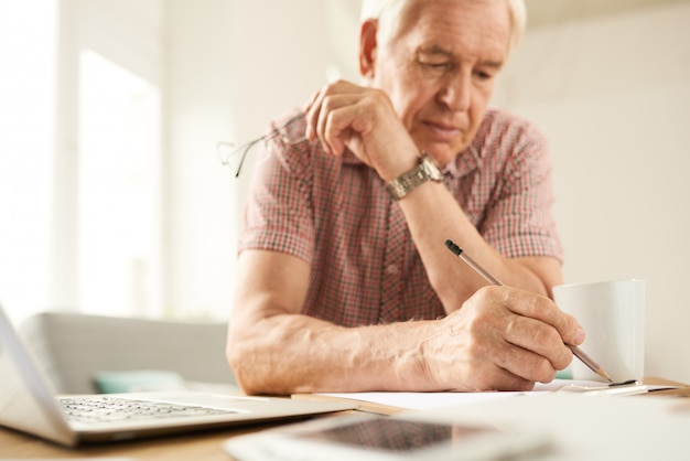 Senior hombre escribiendo en casa