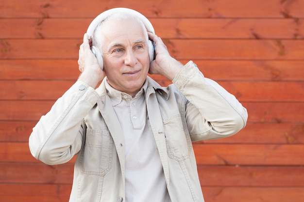 Senior hombre escuchando música en auriculares estéreo, exitoso hombre de negocios senior.