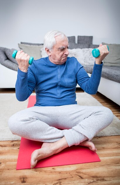 Senior hombre haciendo entrenamiento muscular en casa