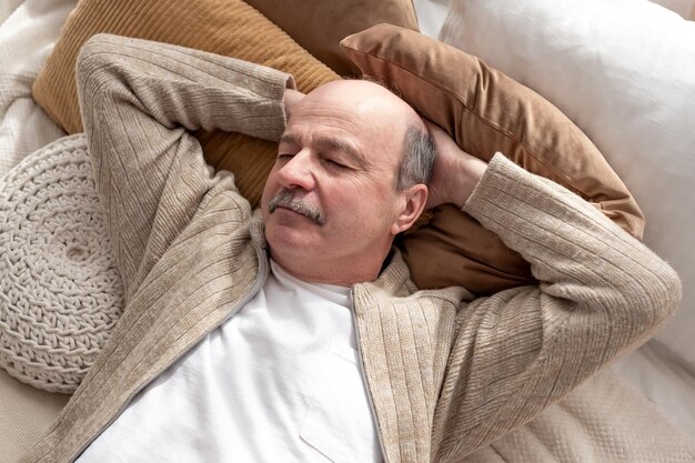 Senior hombre hispano descansando en casa durmiendo en la cama