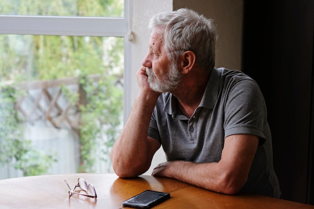 Senior hombre jubilado sentado en casa solo mientras está en cuarentena