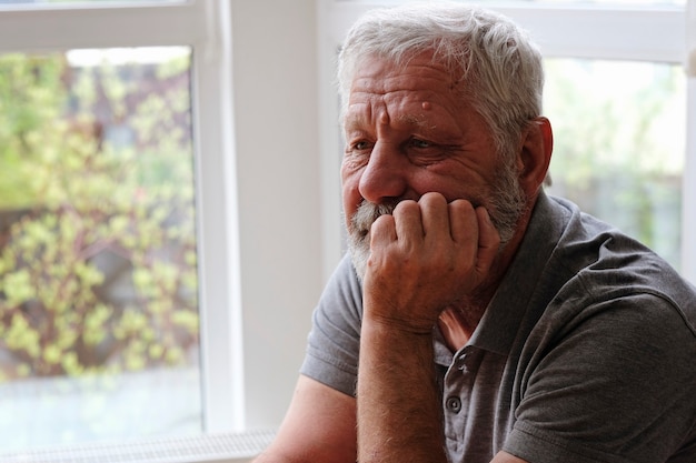 Foto senior hombre jubilado sentado solo en casa mientras está en cuarentena