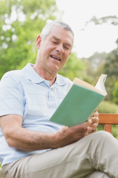 Foto senior hombre leyendo un libro en el parque