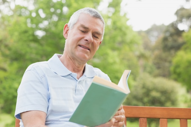 Senior hombre leyendo un libro en el parque