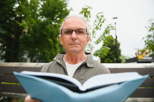 Senior hombre leyendo un libro en el parque