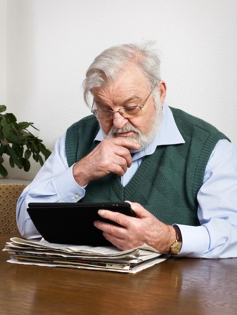 Senior hombre leyendo el periódico en tableta digital