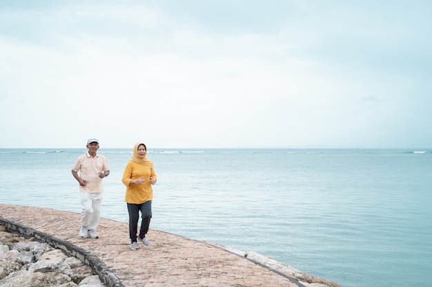 Senior hombre y mujer juntos corriendo en la playa