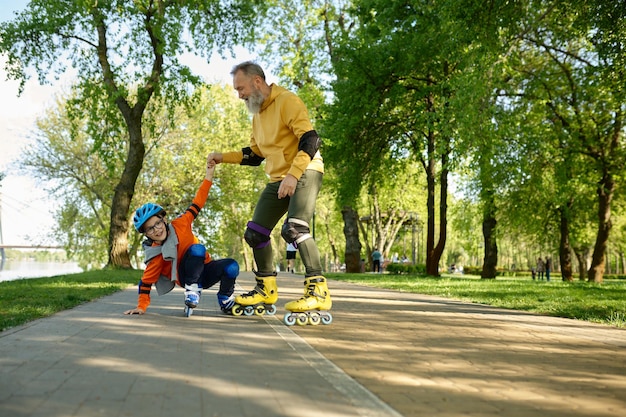 Senior hombre patinaje sobre ruedas con niño en parque urbano