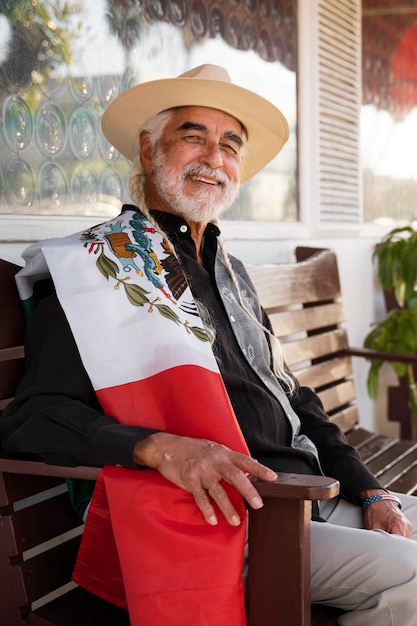 Senior hombre sosteniendo bandera mexicana tiro medio