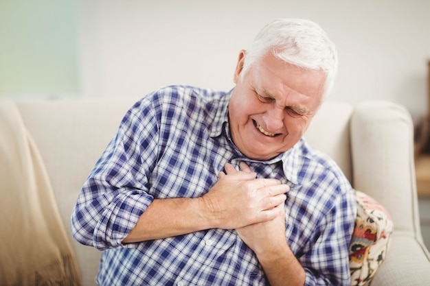 Senior hombre teniendo dolor en el pecho en la sala de estar