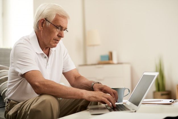 Senior hombre usando laptop en casa