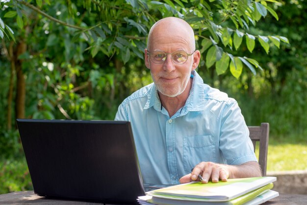 Senior hombre usando laptop en el jardín