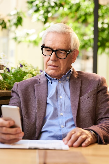 Senior hombre usando smartphone en café