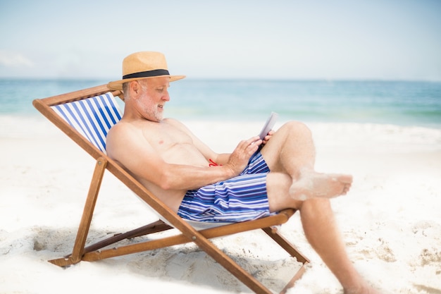 Senior hombre usando tableta en la playa