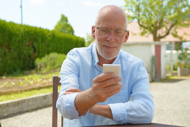 Senior hombre usando el teléfono móvil afuera