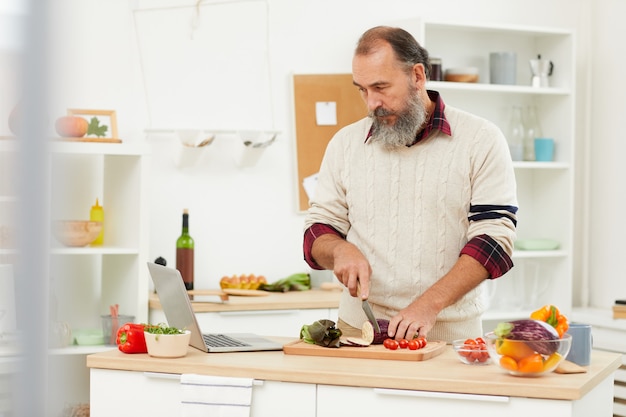 Senior hombre viendo tutorial de cocina