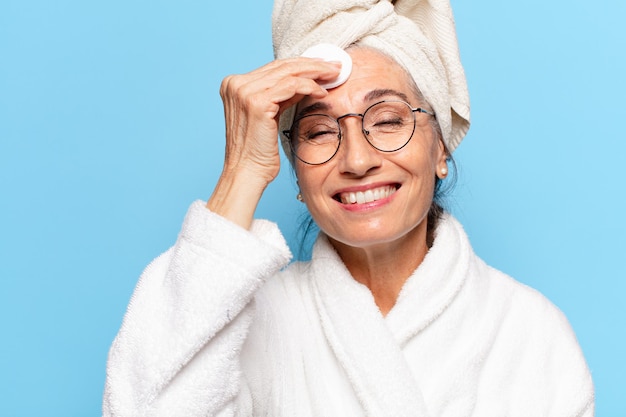 Senior hübsche Frau Gesichtsreinigung oder Make-up nach der Dusche mit Bademantel