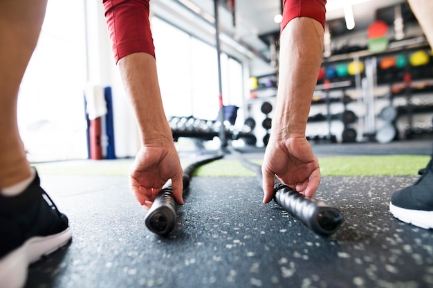 Senior im Fitnessstudio trainiert mit Battle Ropes