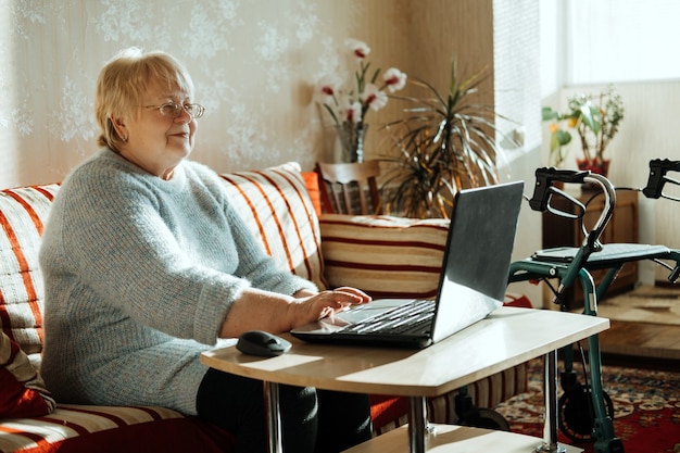 Senior madura mujer caucásica real sincera mirar la pantalla del portátil en casa feliz senior mujer rubia