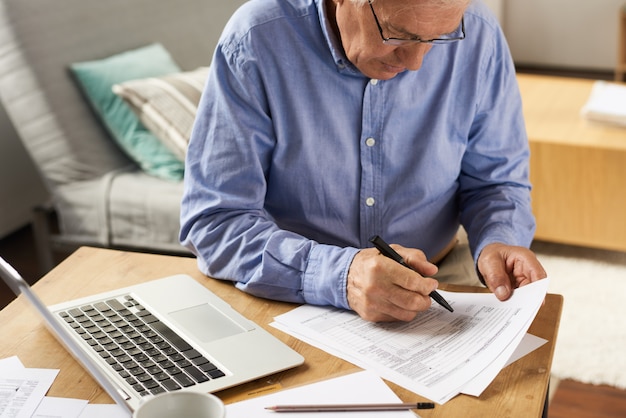 Senior Man Füllen Sie das Antragsformular zu Hause aus