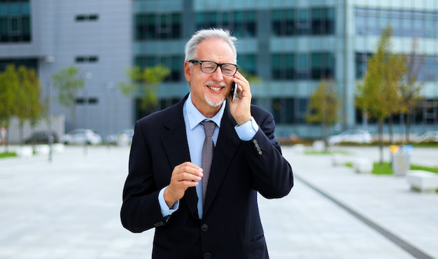 Senior Manager am Telefon zu Fuß im Freien