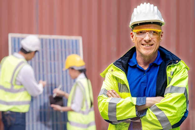 Senior Mann des Fabrikingenieurs, der Vertrauen mit grünem Arbeitsanzugkleid und Schutzhelm steht. Arbeiter Personal, das Solarzellenpanel für den Bau erneuerbarer Energien überprüft. Industriearbeiter tätig.