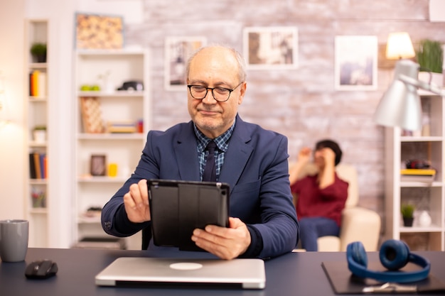 Senior Mann in seinen 60ern mit einem modernen digitalen Tablet in seinem gemütlichen Zuhause