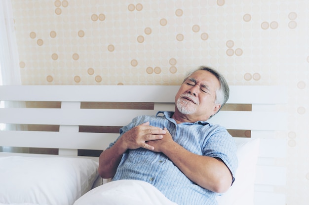 Senior masculino asiático sufriendo de mal dolor en su pecho ataque al corazón en casa